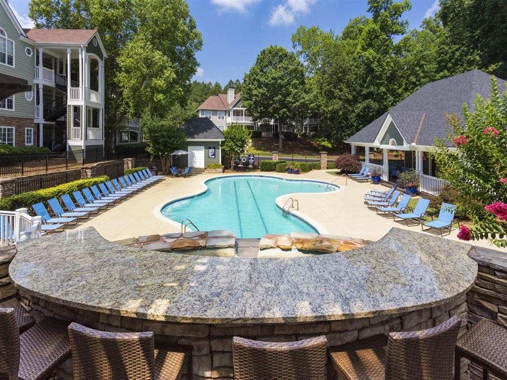 a swimming pool with chairs around it and houses in the background