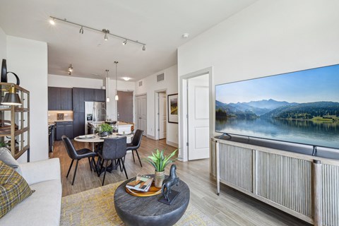 a living room with a large screen tv and a table and chairs