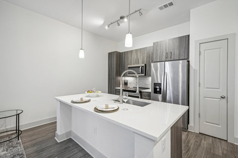 a kitchen with a white counter top and a stainless steel refrigerator