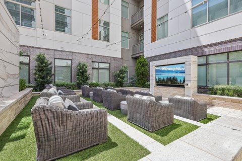 an outdoor lounge area with wicker furniture and a fireplace