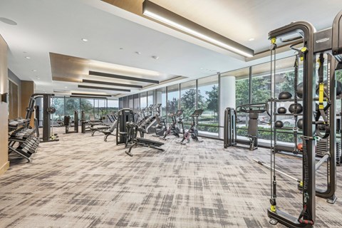 a workout room with weights and other exercise equipment in a building with large windows