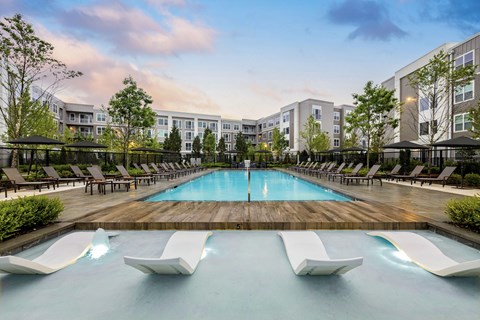 A large pool with lounge chairs and a building in the background.