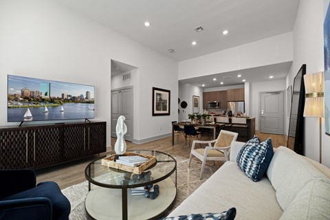 A living room with a glass coffee table and a large painting on the wall.