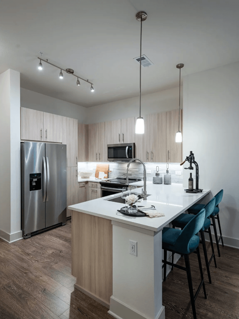 a kitchen with a large island and a stainless steel refrigerator