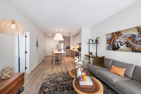 A living room with a grey couch, a coffee table, and a large painting on the wall.