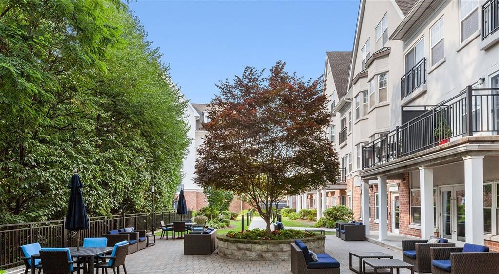 a courtyard with tables and chairs and a tree in front of a building
