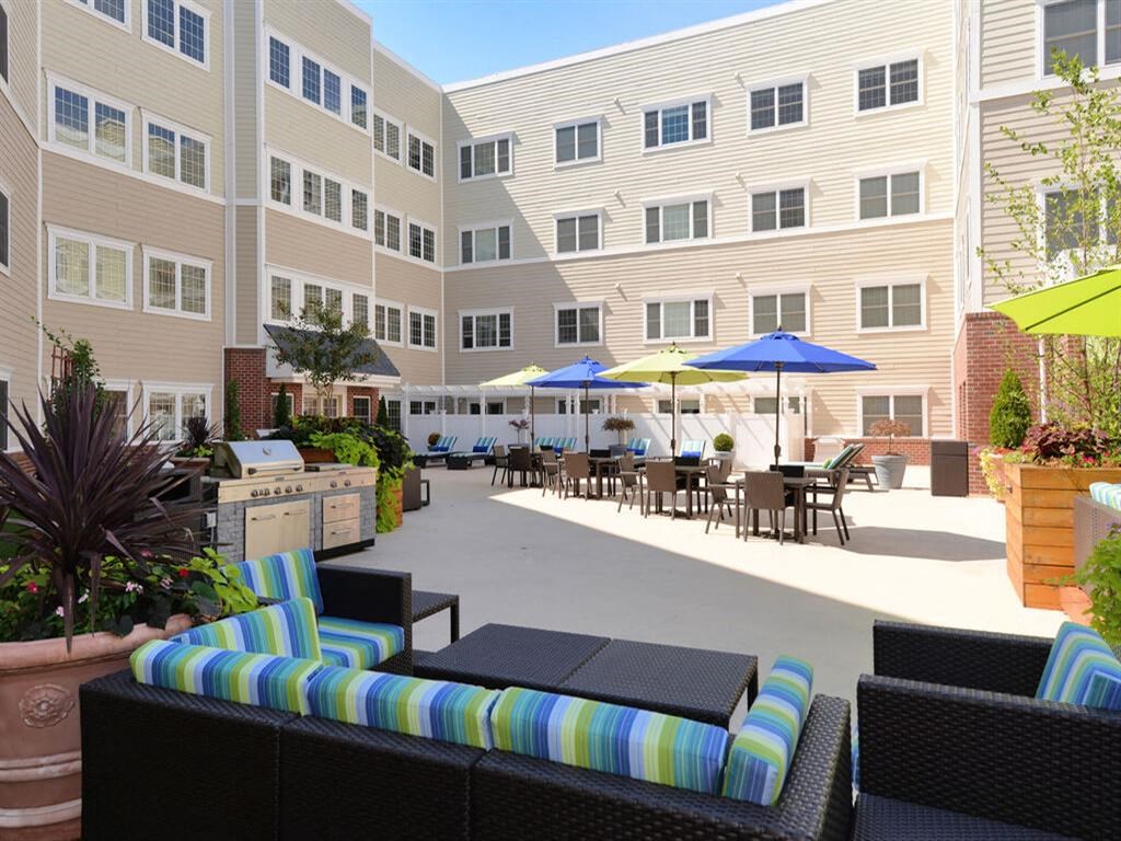 a patio with a grill and tables with umbrellas