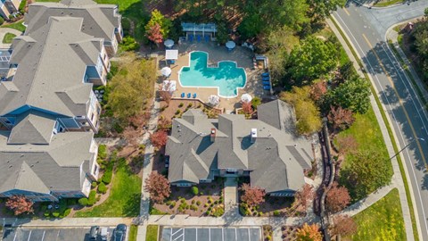 An aerial view of a residential area with houses, a swimming pool, and a parking lot.