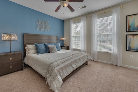 A bedroom with a bed, dresser, and ceiling fan.