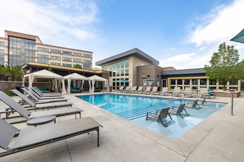 A pool area with sun loungers and a building in the background.