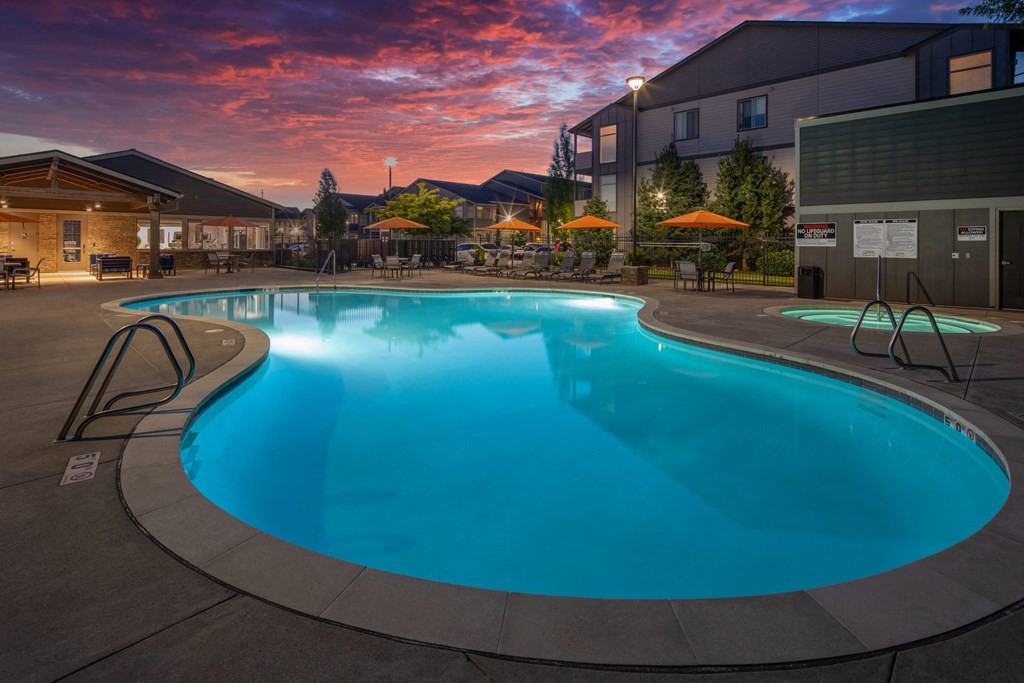 a swimming pool at dusk at a hotel with a sunset in the background