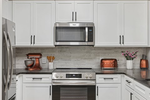 A modern kitchen with white cabinets and stainless steel appliances.