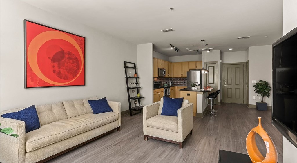 a living room and kitchen with a couch and chairs