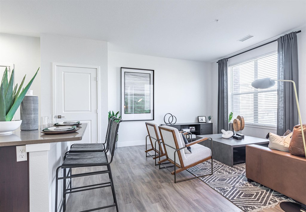 a living and dining area with white walls and hardwood flooring