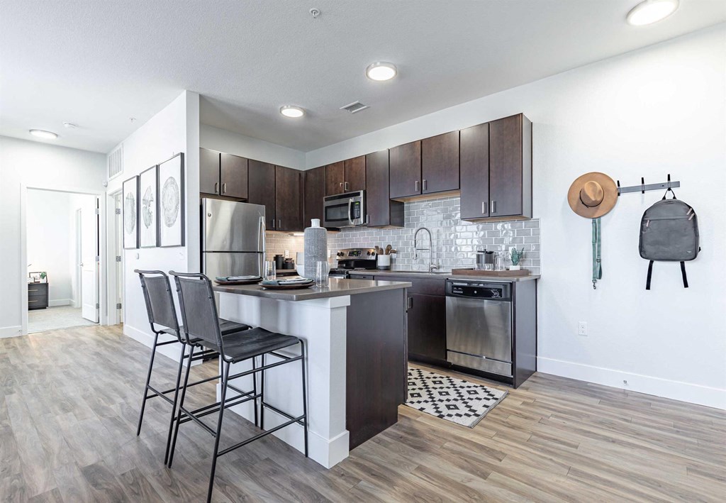 a kitchen with dark wood cabinets and a white island with three stools