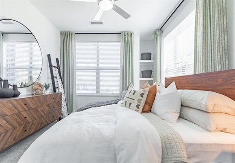 a bedroom with a bed with white bedding and a dresser with a mirror on it at RockVue, Broomfield, CO