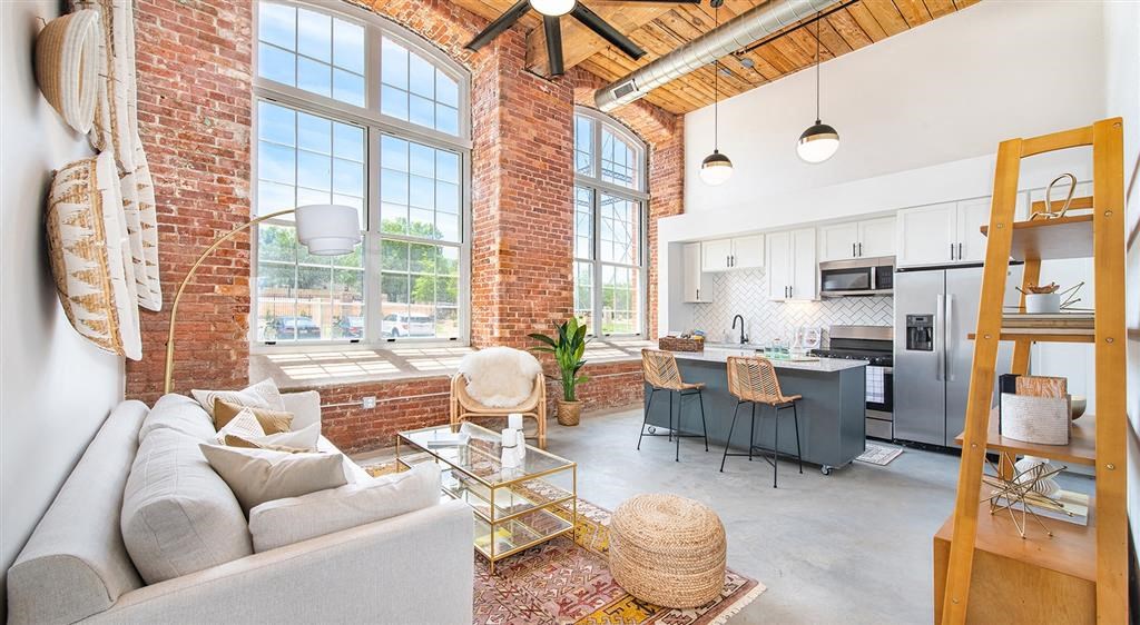 a living room with a couch and a kitchen with an exposed brick wall