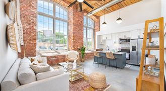 a living room with a couch and a kitchen with an exposed brick wall
