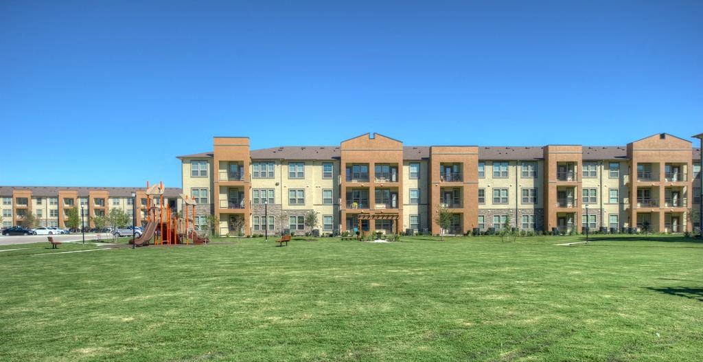 a large grassy area with a playground in front of a building