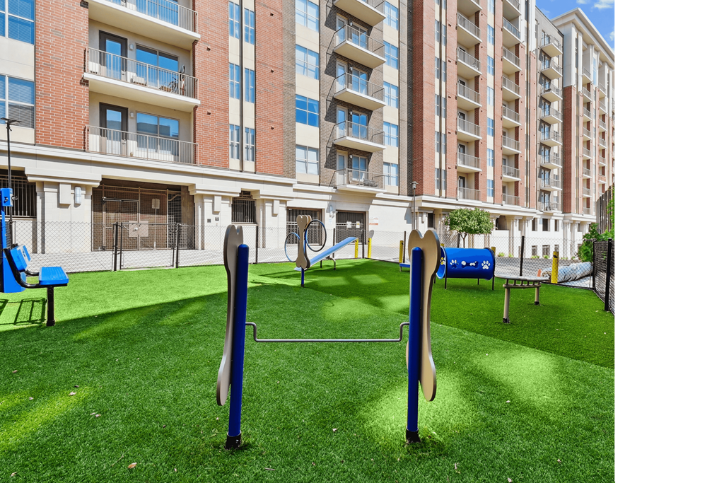 A playground with a blue slide and a green lawn in front of a brick building.