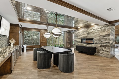 A modern kitchen with a stone fireplace and a dining table with chairs.
