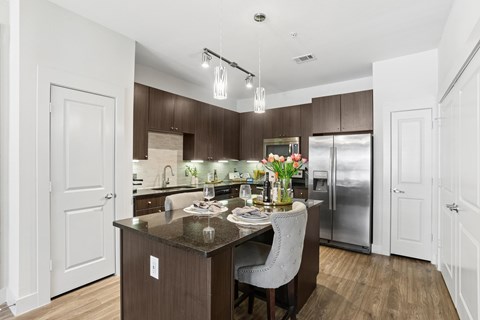 A modern kitchen with a dark brown island and white walls.