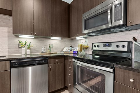 A modern kitchen with dark wood cabinets and stainless steel appliances.
