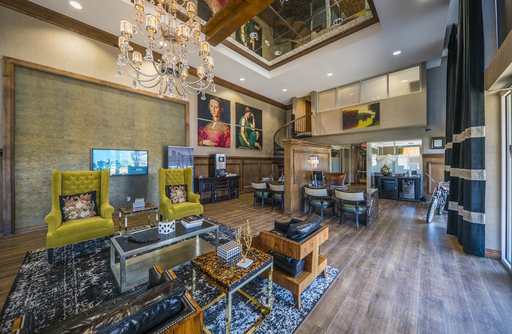A large, luxurious living room with a chandelier, two yellow armchairs, and a wooden coffee table.