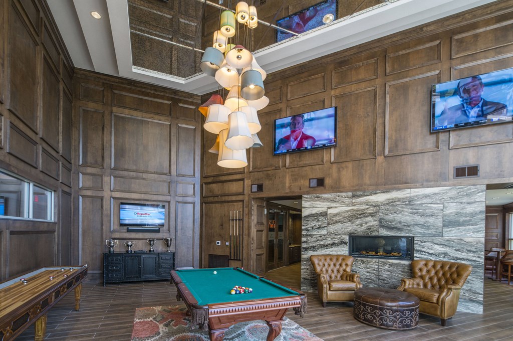 A billiard table is in the middle of a room with a fireplace and a television.