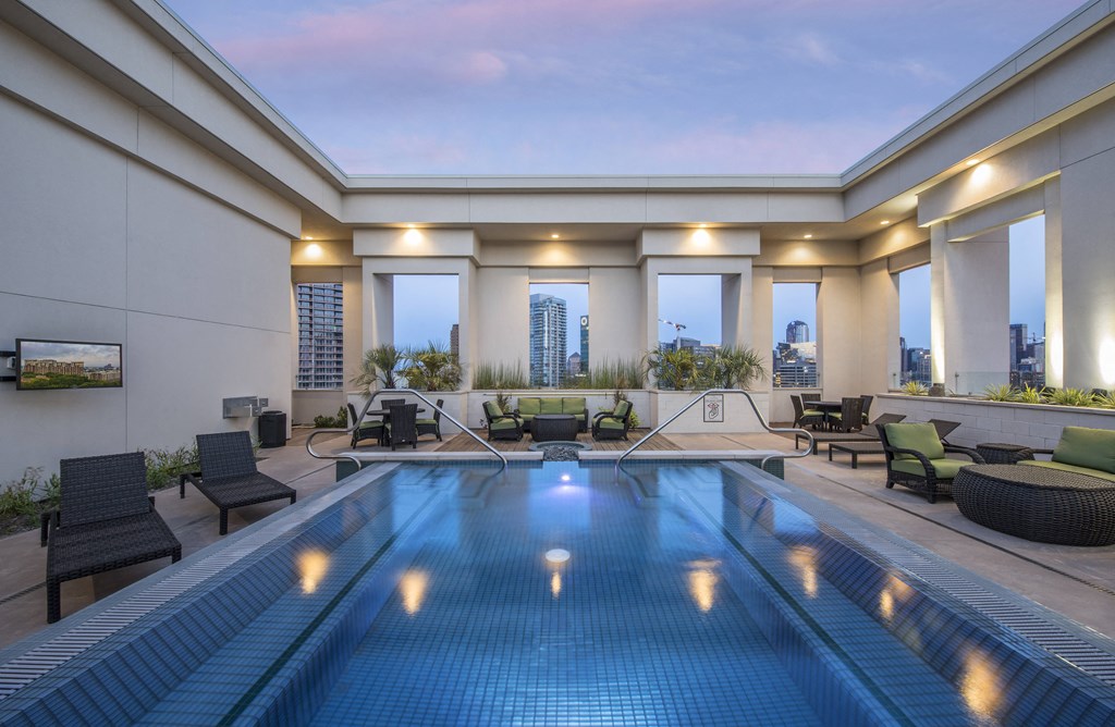 A swimming pool in a patio with lights on.