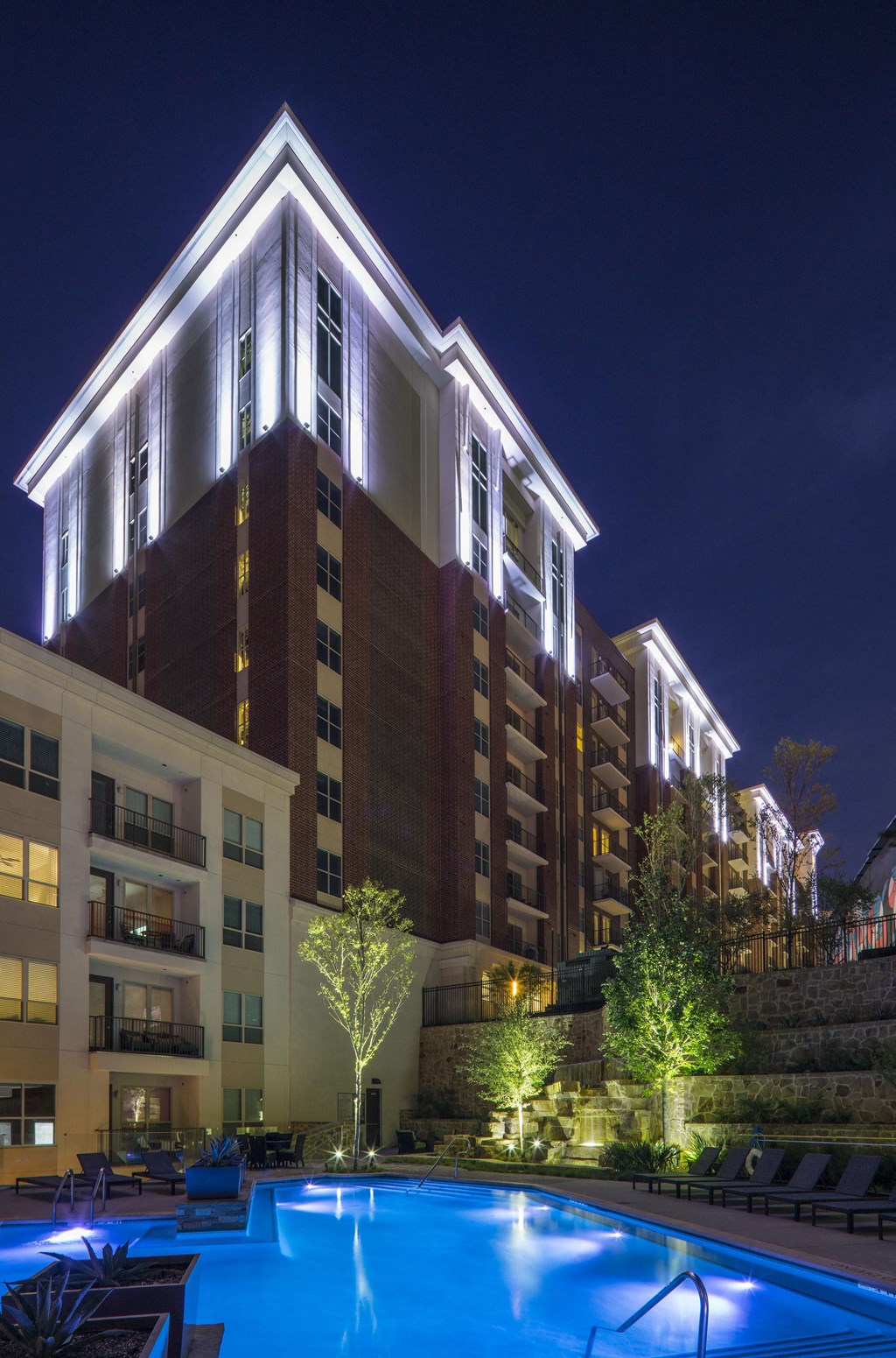 A large building with a pool in front of it at night.
