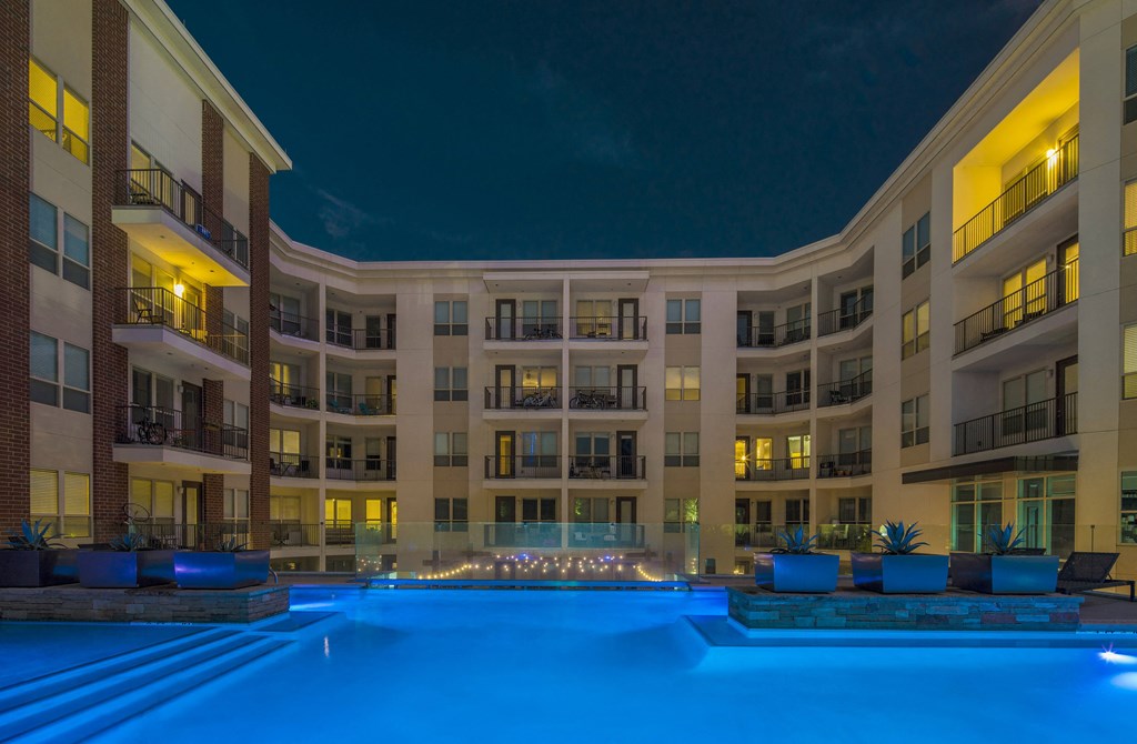 A large building with a pool in front of it at night.