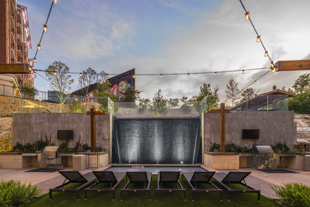 A modern outdoor seating area with a water feature and string lights.