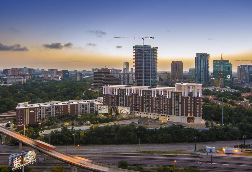 A cityscape with a large building in the foreground and several cranes indicating construction.