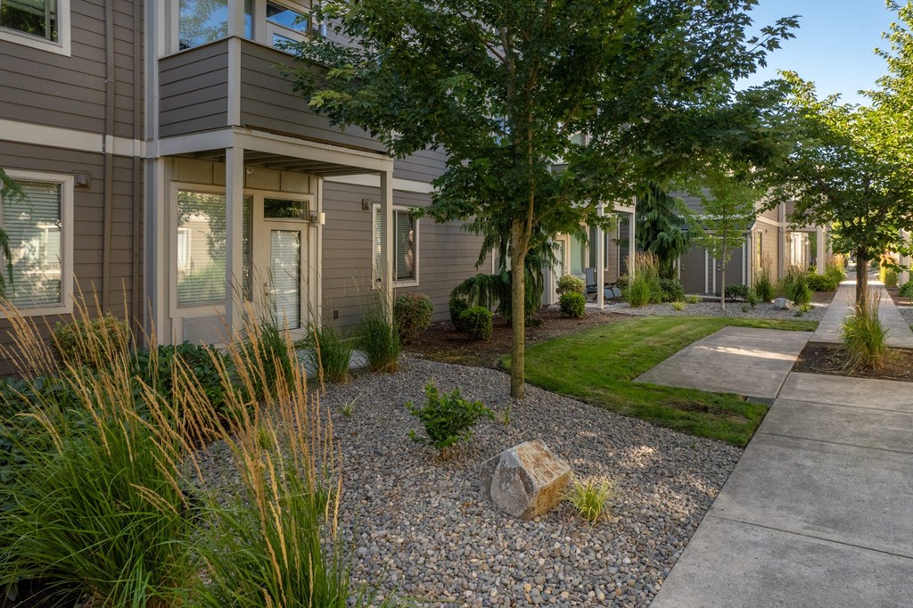 a front yard with a tree and a rock in front of a house