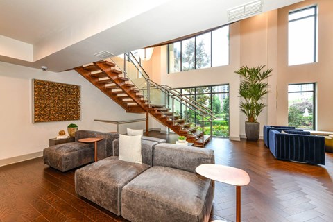 A living room with a grey couch and a staircase.