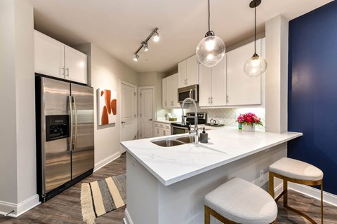 A modern kitchen with a white island and stools.