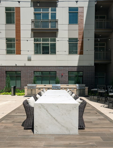an outdoor table with chairs in front of an apartment building