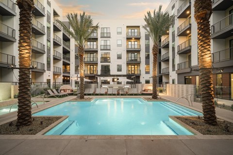 A swimming pool surrounded by palm trees and apartment buildings.