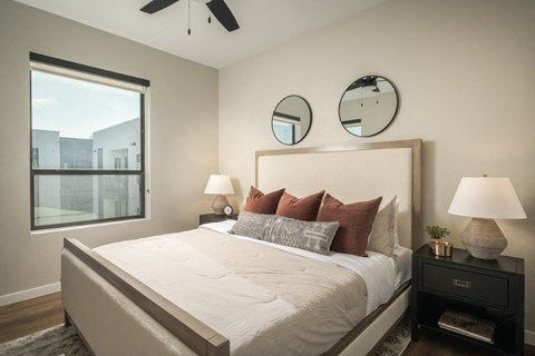 A bedroom with a large bed, two lamps, and a ceiling fan.