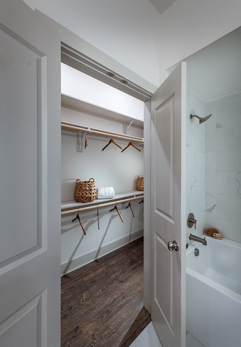 a walk in closet with a shower and a shelf with hangers