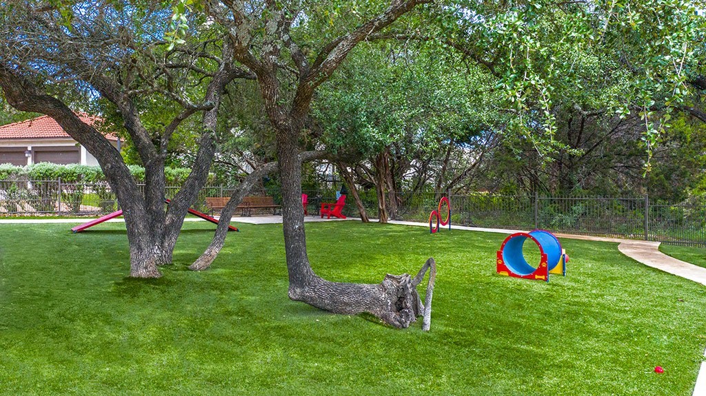 Enclosed pet park with agility equipment..