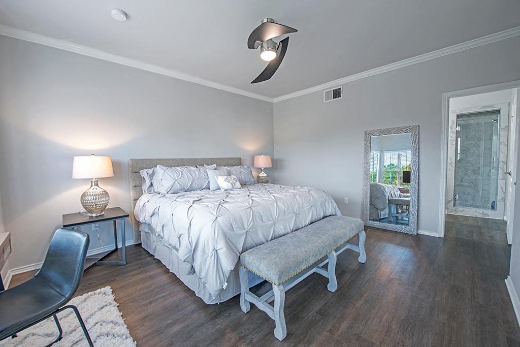 A bedroom with a bed, chair, and a table with a lamp on it.