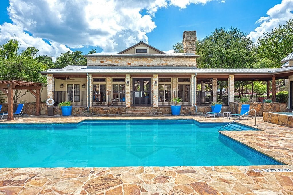 the pool is in front of a house with a porch and a large pool