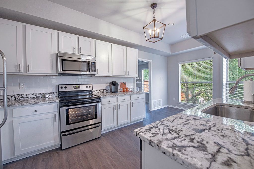 A kitchen with a marble counter top and stainless steel appliances.