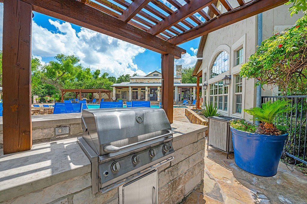 a barbecue grill on a patio with a pergola