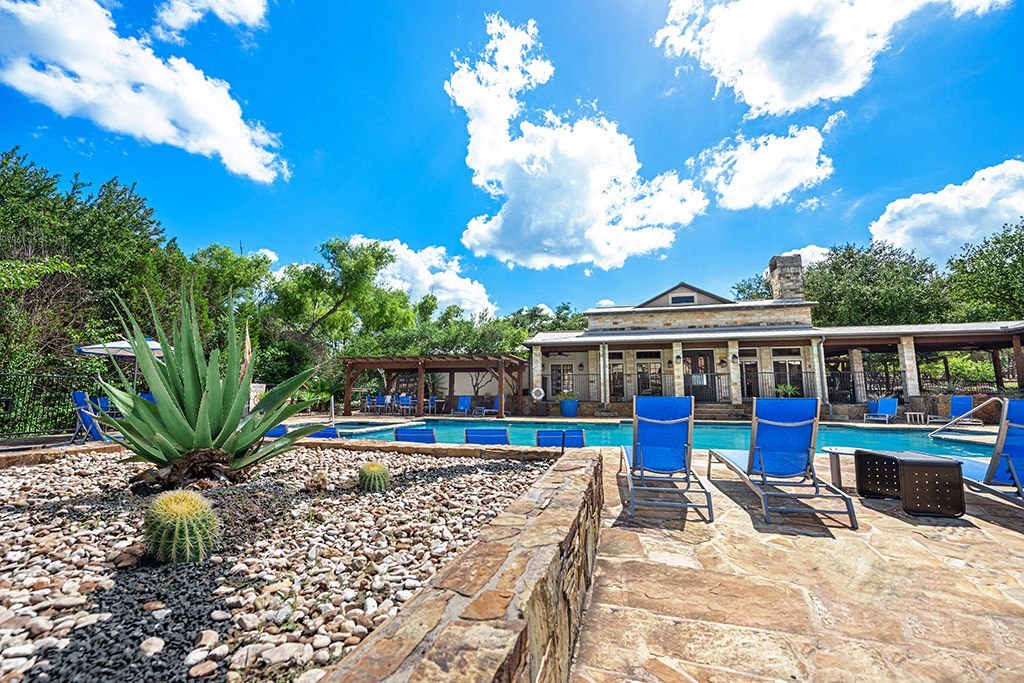 a backyard with a pool and a house with blue chairs