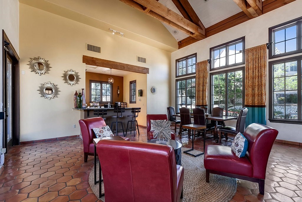 a large living room with red chairs and a bar and windows