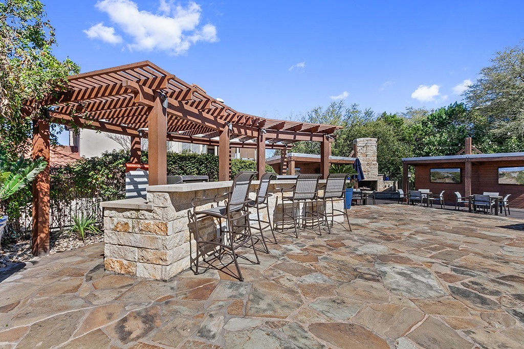 a patio with a stone bar and a wooden pergola