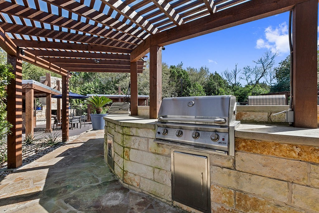 an outdoor kitchen with a grill under a patio